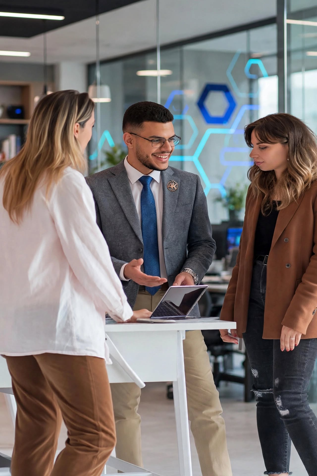 Three colleagues reviewing work together on a laptop at a standing desk